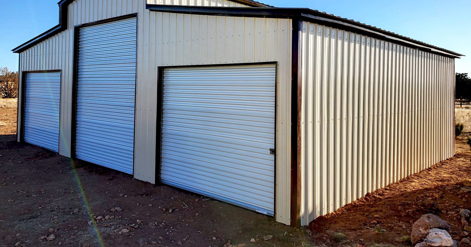 Cream steel barn with dual lean-tos and white roll-up doors