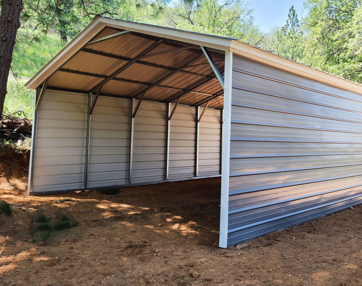 Silver steel carport with partial side panels in wooded setting