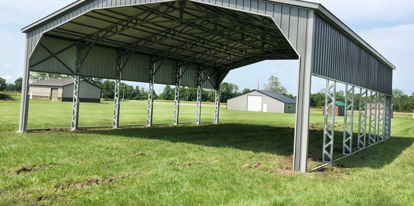 Wide-span silver steel carport pavilion on open field