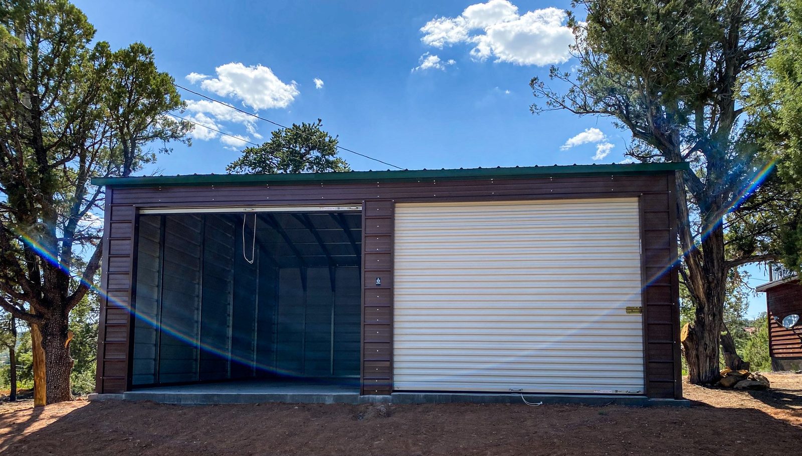 Brown steel garage with green roof and white roll-up door