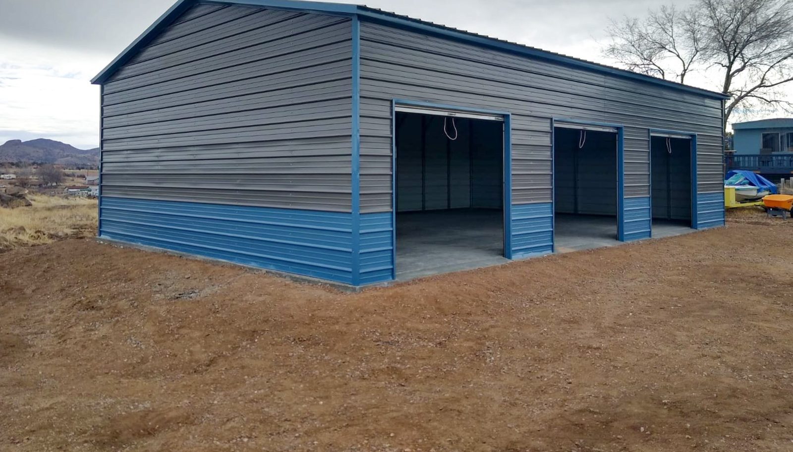 Two-tone gray and blue steel garage with double open bays in desert setting