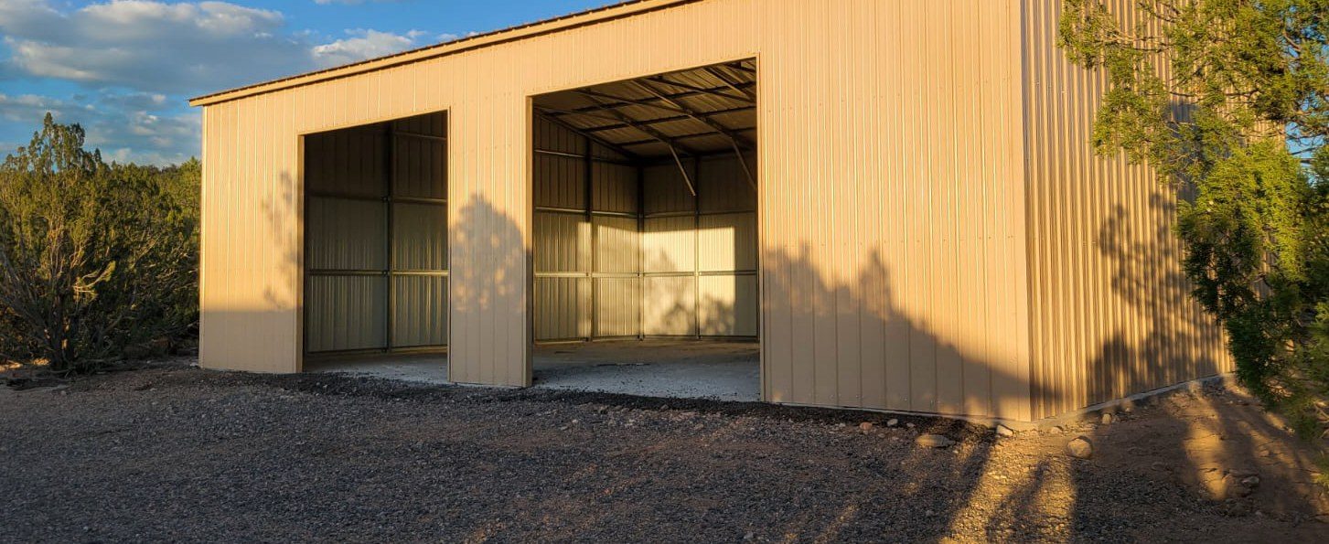 Tan two-car steel garage with twin roll-up doors in evening light