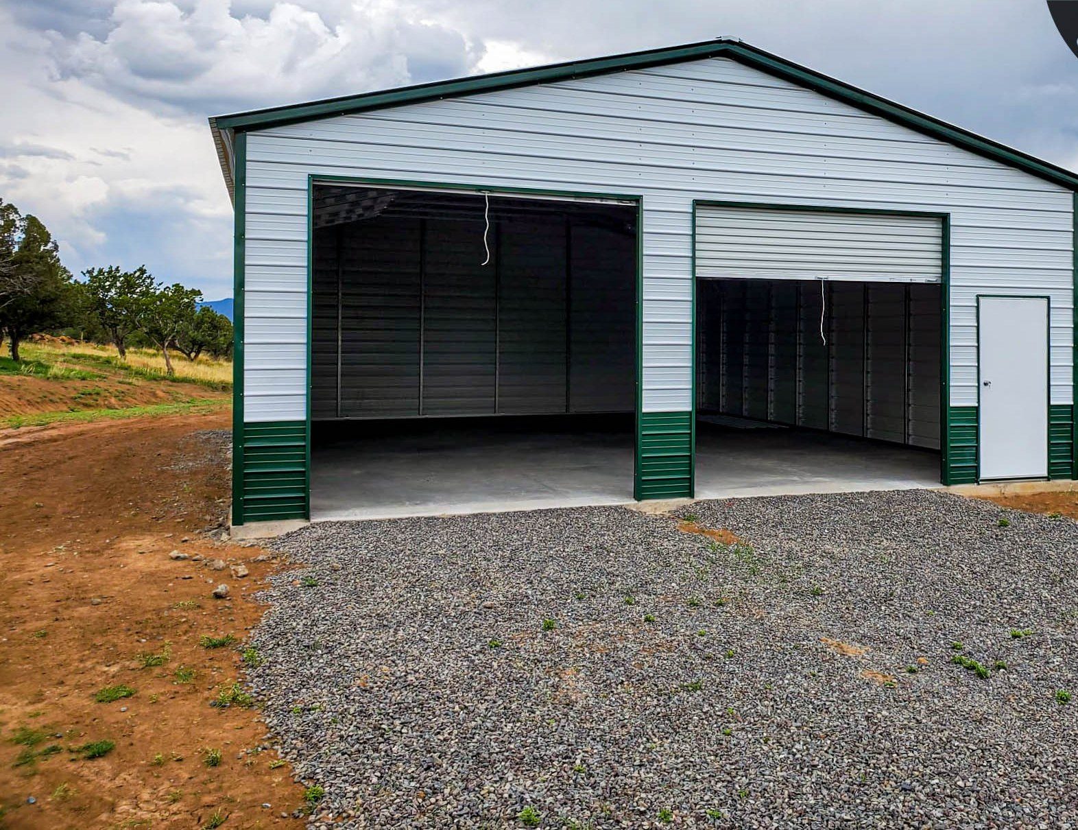 White and green steel garage with vertical roof in mountain setting