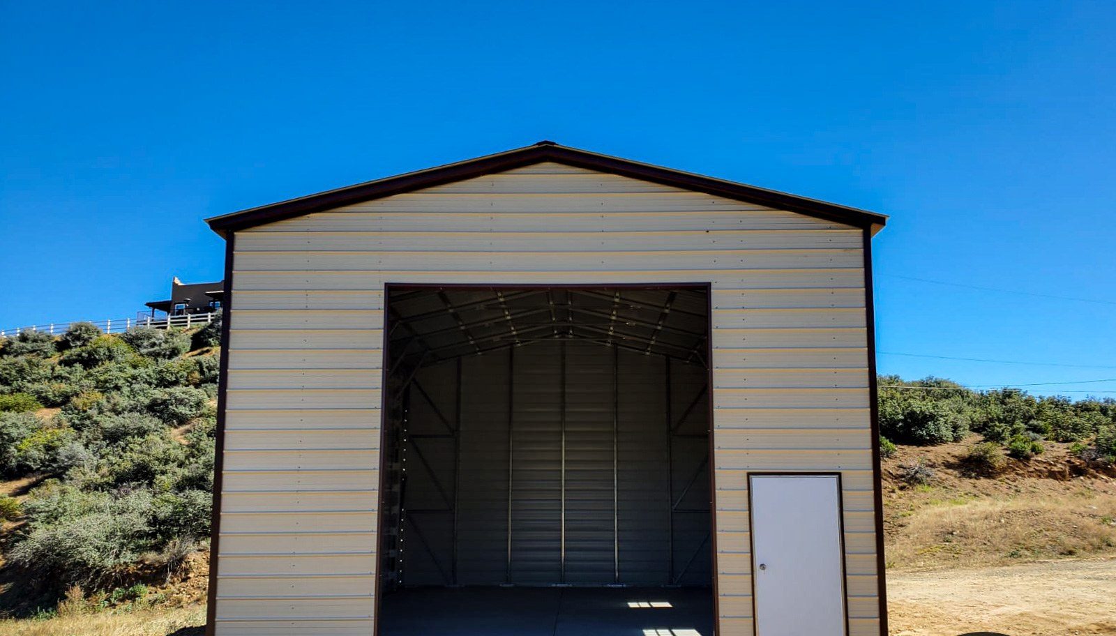 Tall single-bay steel RV garage with roll-up door and walk-in
